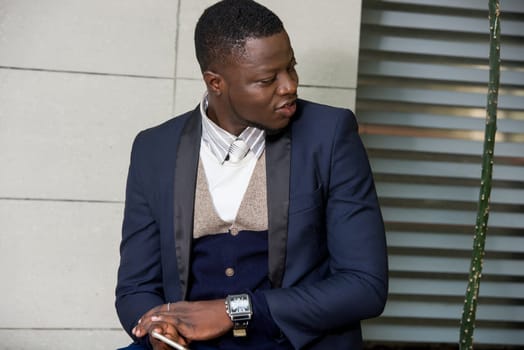 young man sitting in a suit looking sideways smiling.