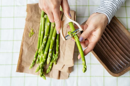 A woman cleans asparagus at the table. Clean and wholesome food for health. Vegetarianism, raw food