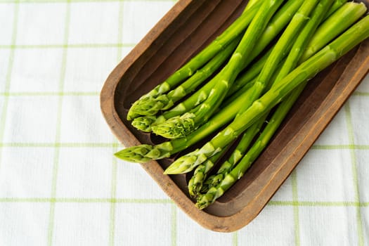 Green asparagus on a wooden plate. Clean and wholesome food for health. Vegetarianism, raw food. Healthy food concept