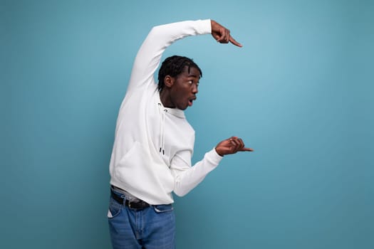 inspired man young brunet african man shows with hand to advertisement offer on blue isolated background.