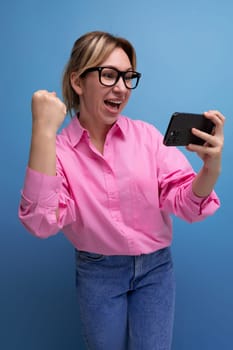 young confident blond woman with ponytail and glasses dressed in a trendy pink shirt for the office watching video.