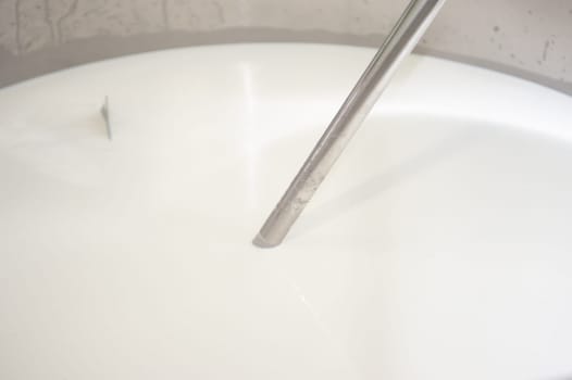 Cheesemaker cooking stirring italian bufalo organic milk in stainless steel caudrons, to produce ricotta cheese, italian food excellence worldwide export.