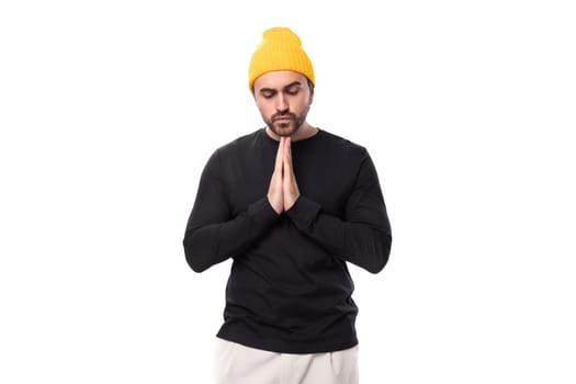 young brunette European brutal man in a black jacket prays and hopes.