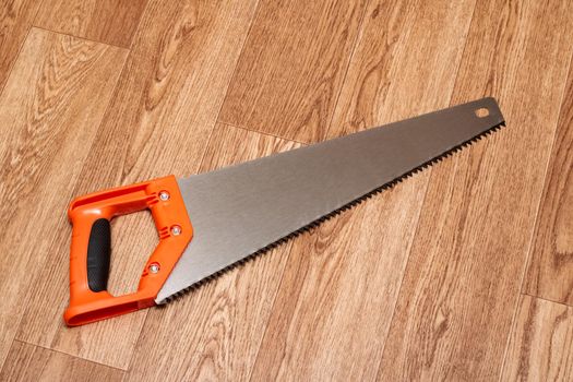 Saw with a plastic handle on a wooden table close up