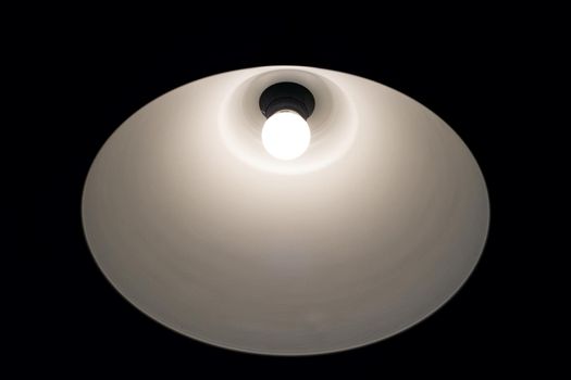 Bright white light bulb with a white lamp in the dark close up