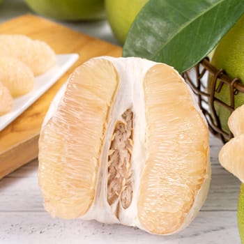 Fresh peeled pomelo, grapefruit, shaddock on bright wooden table background. Seasonal fruit for Mid-Autumn Festival, close up, copy space.