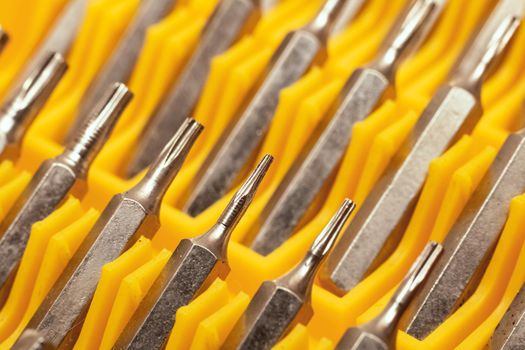 Screwdriver bits in a yellow plastic container close up