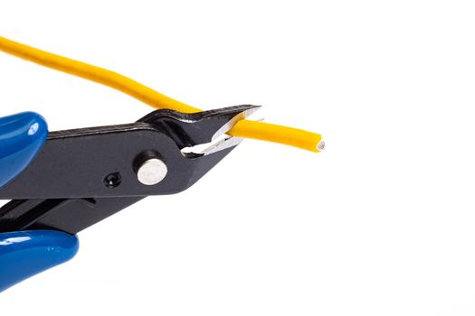 Blue wire cutter cuts yellow wire isolated on white background close up