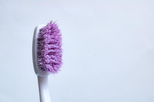 Toothbrush with purple pile close-up on a white background, copy space