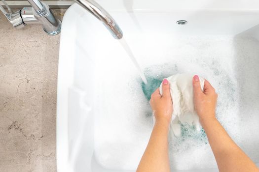 Female hands washing color clothes in basin