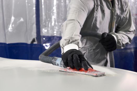 Auto mechanic buffing and polishing car in auto repair shop