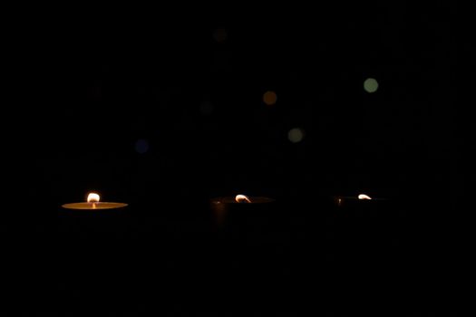 Three small candles in the dark close up