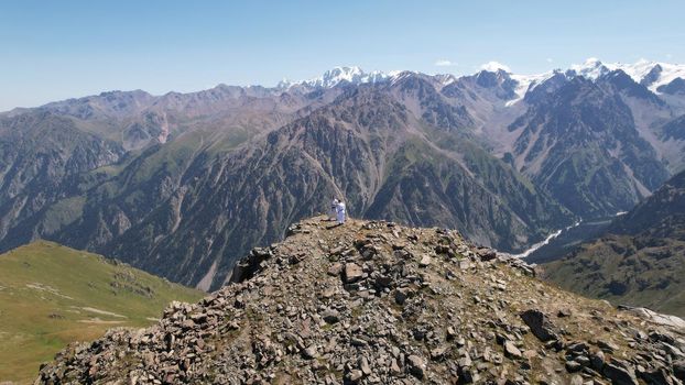 Karate training on a peak among mountains. Karate elements in a white kimono with a black and blue belt. Sparring, card, punches and kicks are performed by two guys. Rocks, snowy mountains and a cliff