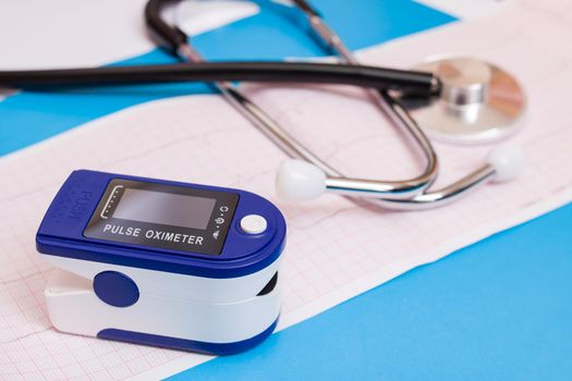 One pulse oximeter and stethoscope on a blue background