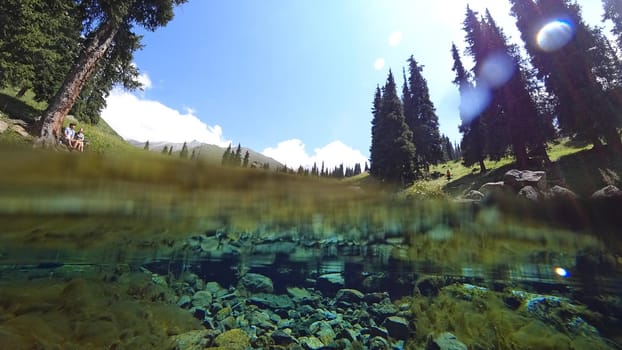 An incredible underwater world of a mountain river. Crystal clear clear water. Yellow rocks and green-brown algae. The rays of light are refracted into a blue color in the distance. An unusual world