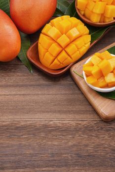 Fresh mango,beautiful chopped fruit with green leaves on dark wooden table background. Tropical fruit design concept. Flat lay. Top view. Copy space