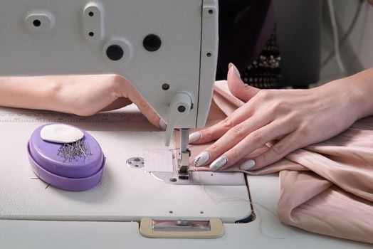 Woman using sewing machine in tailor studio or modern atelier shop