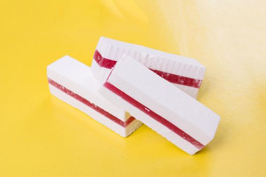 White cake with fruit jam on yellow background close up