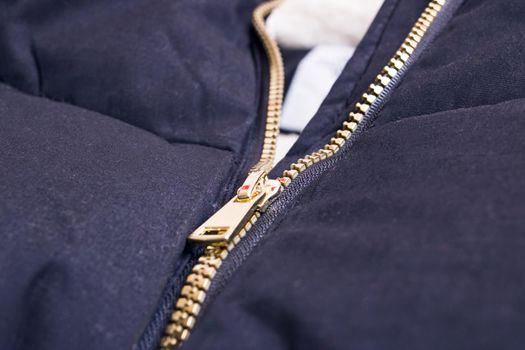 Metallic yellow zipper on a black jacket close up