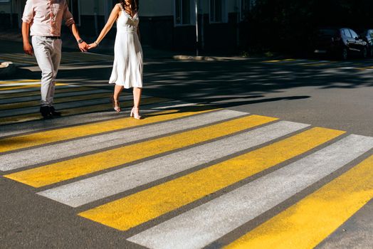 A happy couple crosses the road at a bright yellow pedestrian crossing