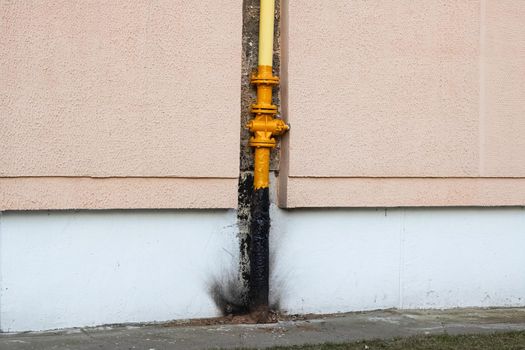 Yellow water pipe on a house wall close up