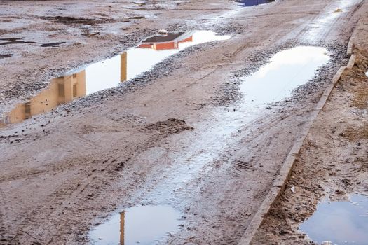 Puddles and mud on a sandy road close up