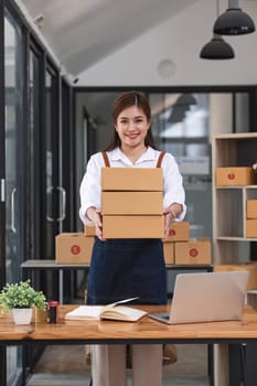 Portrait of Asian young woman SME working with a box at office the workplace.start-up small business owner, small business entrepreneur SME or freelance business online and delivery concept...