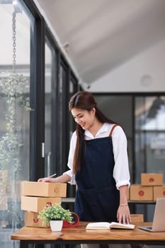 Shipping shopping online ,young start up small business owner writing address on cardboard box at workplace.small business entrepreneur SME or freelance asian woman working with box at office.