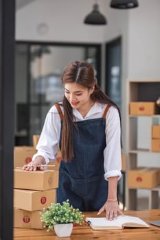 Shipping shopping online ,young start up small business owner writing address on cardboard box at workplace.small business entrepreneur SME or freelance asian woman working with box at office.