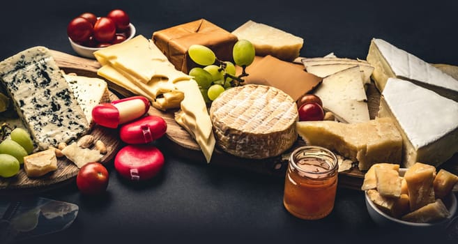 Different kinds of cheese served with grape, honey and tomato. Organic parmesan, brie and camambert set with nuts delicatessen collection