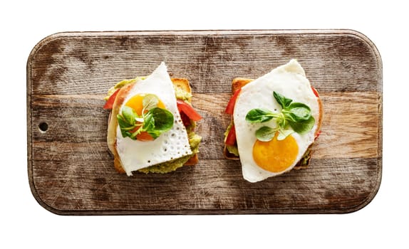 Toasted bread with egg, tomato and spinach for healthy protein breakfast on wooden table. Tasty morning sandwich for fast diet