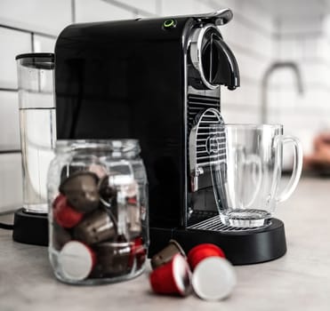 Coffee machine with capsules and transparent cup at domestic kitchen at home. Espresso caffeine beverage maker and modern mug