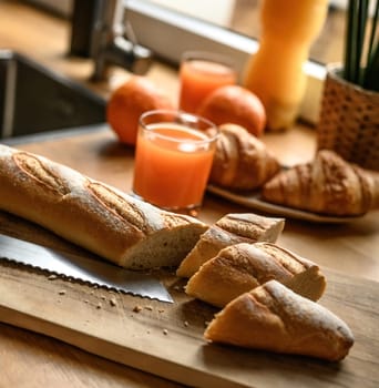 Fresh baguette on a cutting board at the kitchen. Cooking fresh french breakfast.