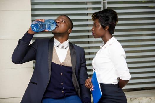 Group of business people standing outside building. Businessman taking a break drinking drinking water and discussing with his co-worker