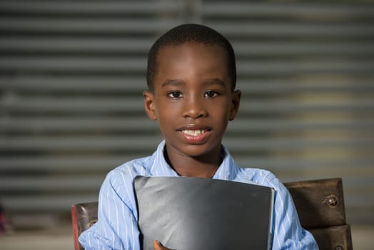 Happy satisfied child carrying in primary school. Close Up African schoolboy face standing outside.