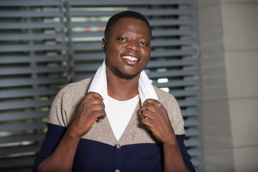 young man standing in a room with towel on his neck and smiling at the camera.