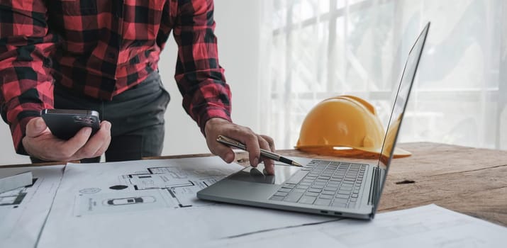 Concept architects, engineer holding pen pointing equipment architects On the desk with a blueprint in the office.