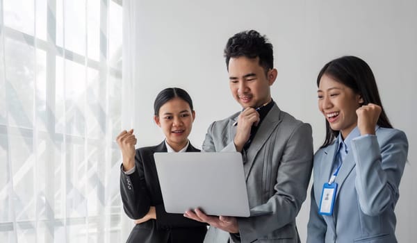 Solving problems as one team. Asian young team of male and female working together while sitting at their working place in office, enjoy, looking at the camera...