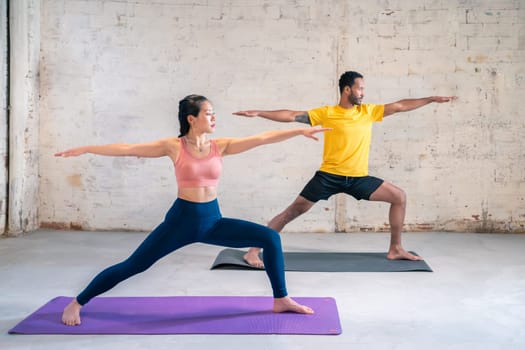Mixed race sporty man and girl doing exercise. Multi ethnic couple On Mats Doing Yoga Exercises Together. High quality photo