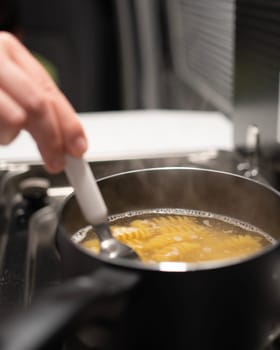 close up of woman hand cooking fresh pasta food on a stove inside a caravan