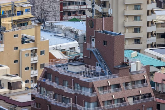 Brown building with wrap-around verandas and rooftop balcony in dense city. High quality photo