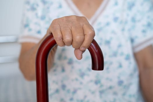 Asian elderly disability woman holding waling stick, wood cane, round handle, walking aid for help to walk.