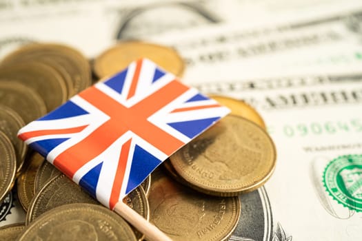 Stack of coins with United Kingdom flag and US dollar banknotes.