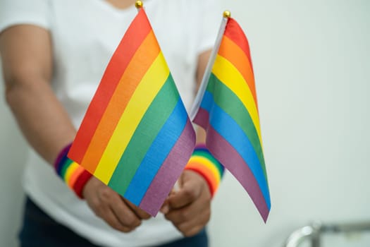 Woman holding LGBT rainbow colorful flag, symbol of lesbian, gay, bisexual, transgender, human rights, tolerance and peace.