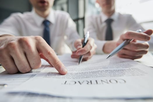 Close-up of businessmen reviewing a close-up contract while sitting at a table