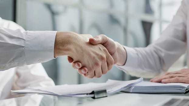 Close up businessman shaking hands with caucasian client.