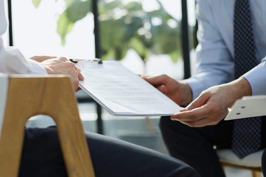 Two business employees reviewing documents in open folder. Paperwork concept