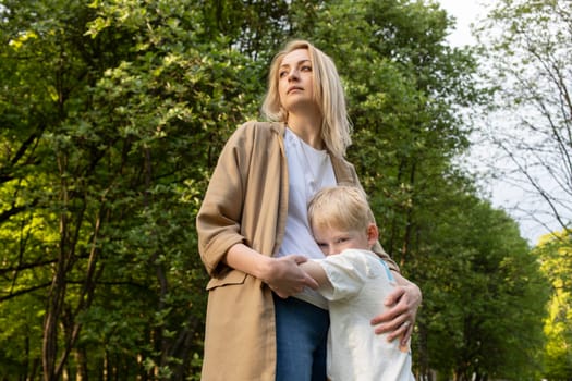 Little Caucasian 7 Yo Boy Hugs His Mother Tight in Park. Mom's Support And Care. Summer Time. Motherhood, Family Leisure Time. Children's Day. Horizontal Plane. Copy Space For Text. High quality photo