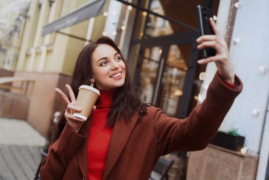 Young happy woman taking selfies on her cell phone on the street.