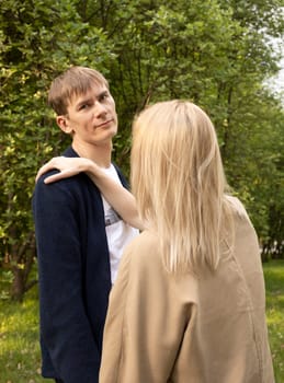 Couple In Park. Back View Of Woman Holding Hand On Man's Shoulder. Relationship, Togetherness. Enjoying Time Together. Feelings. Vertical Plane Summer Time. High quality photo